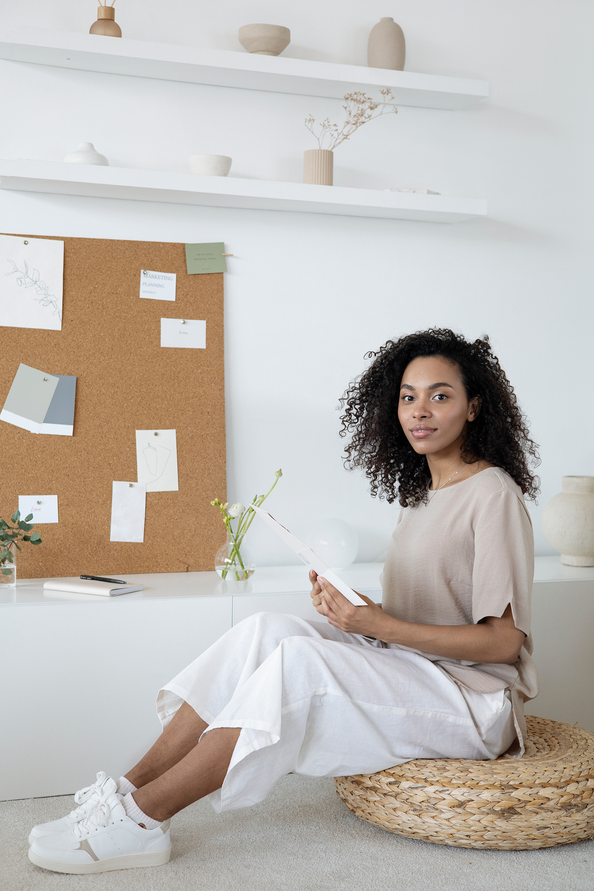 A Woman with Curly Hair Sitting Near a Bulletin Board